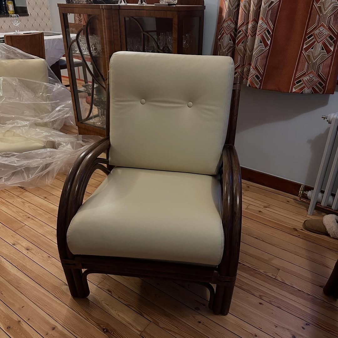 A chair made of curved cane with cream-coloured leather cushions.