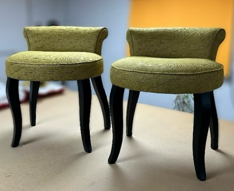 A set of circular chairs with very low backrests. They are covered in an olive green fabric with a geometric pattern. The chair legs are black.